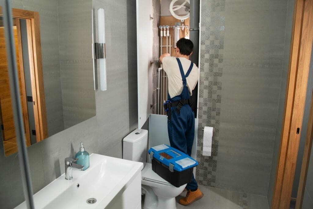 Plumber Fixing Pipes in Bathroom